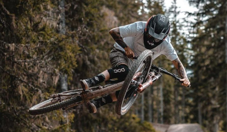 Person on a mountain bike performing a jump in a forest setting